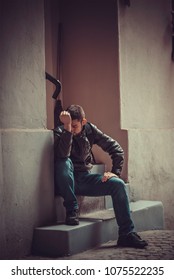 Young Depressed Man Sitting In The Dark Alleyway, Feeling Sadness And Pain