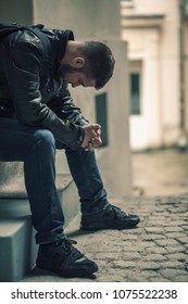 Young Depressed Man Sitting In The Dark Alleyway, Feeling Sadness And Pain