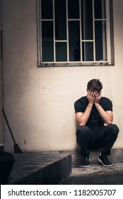 Young Depressed Man Sitting In The Dark Alleyway, Feeling Sadness And Pain