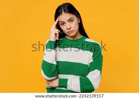 Young depressed sad dissatisfied brunette latin woman 30s wear casual cozy green knitted sweater look camera prop up chin isolated on plain yellow background studio portrait People lifestyle concept