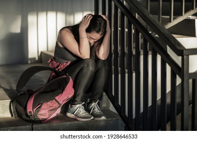 young depressed and scared Asian Korean student girl suffering abuse and harassment at school victim of bullying and discrimination sitting on college staircase tormented - Powered by Shutterstock