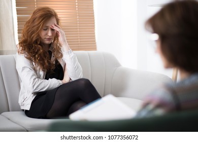 Young depressed woman in psychotherapy, talking to her therapist about her problems