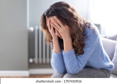 Young depressed woman sitting on sofa in living room. She feeling sad and worried suffering depression in mental health. Problems and broken heart concept. - Powered by Shutterstock