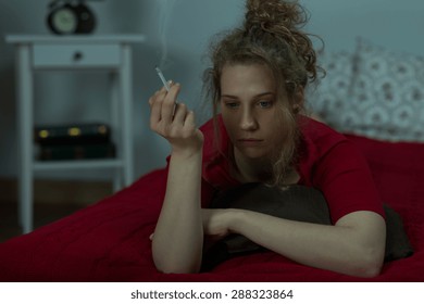 Young Depressed Woman Is Smoking In Her  Bed 