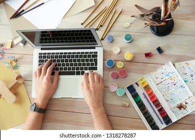 Young designer using laptop on wooden table
