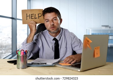 junger verzweifelter Geschäftsmann, der unter Stress am Computer-Schreibtisch arbeitet und ein Schild mit der Bitte um Hilfe sucht müde und überfordert durch schwere Arbeit an modernen Büroarbeitsplätzen erschöpft und überfordert