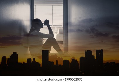 Young Desperate Woman Praying At Home Against City Background. 