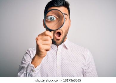 Young Detective Man Looking Through Magnifying Glass Over Isolated Background Scared In Shock With A Surprise Face, Afraid And Excited With Fear Expression