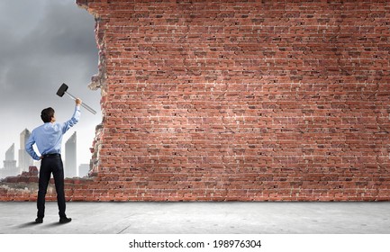 Young determined businessman with hammer in hands - Powered by Shutterstock