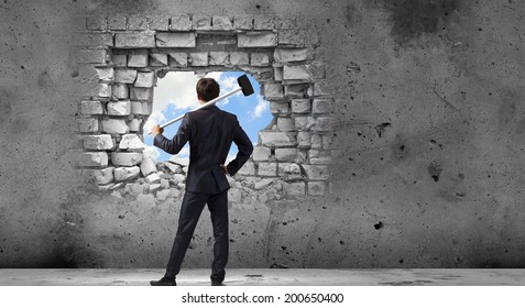 Young determined businessman with hammer in hands - Powered by Shutterstock