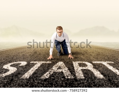Young determined businessman kneeling at a start line 