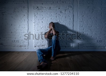 Young devastated depressed man crying sad feeling hurt suffering Depression in Sadness Emotional pain and human expression Loneliness and Heartbroken concept with copy space and dark mood light.