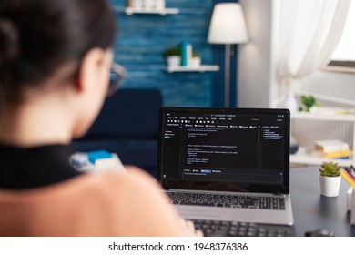 Young developer programming software typing html code deloping application for mobile use. Student working at infographics javascript using laptop computer while sitting at desk in living room