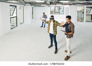 Young developers testing new virtual reality application in empty room of buildng under construction