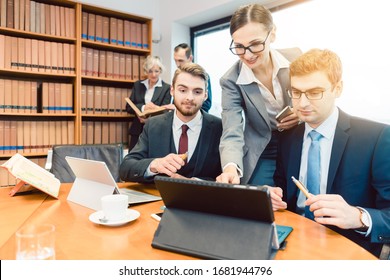 Young But Diligent Lawyers In Their Law Firm Working On Computer With Books In Background