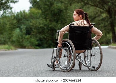 A young disabled girl sits in a wheelchair on the street. The concept of a wheelchair, disabled person, full life, paralyzed, disabled person, health care - Shutterstock ID 2037669224