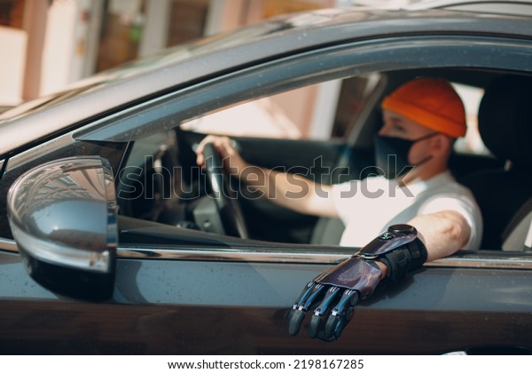 Young disabled man driver with artificial prosthetic\
hand driving vehicle car