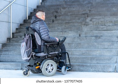 young disabled man in a electric wheelchair in front of stairs