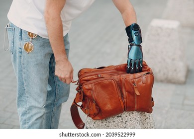 Young disabled man hold and zips backback leather bag with artificial prosthetic hand in casual clothes