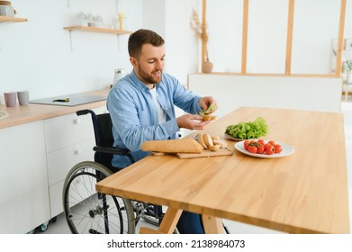 Young Disabled Man Sitting On Wheel Chair Preparing Food In Kitchen