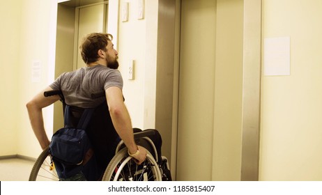 Young disabled man in a wheelchair waiting for elevator in the rehabilitation clinic.