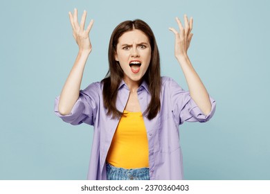Young displeased sad woman she wears purple shirt yellow t-shirt casual clothes spread hands cream shout look camera isolated on plain pastel light blue background studio portrait. Lifestyle concept