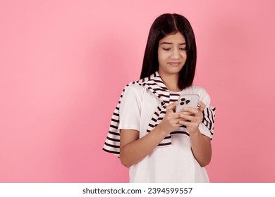 Young dissatisfied teenage girl with bag on pink background in studio. - Shutterstock ID 2394599557