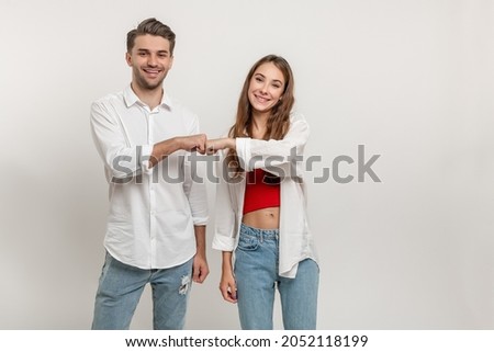 Young diverse couple give fist bump, agree to bring plan to life, smile broadly, have good friendly partners, isolated over white wall