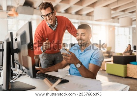 Young diverse coworkers using a smartphone in a startup company office