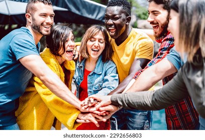 Young diverse friends stacking hands on positive union mood - Multi racial unity culture among students having fun together - Life style friendship concept with gen z people - Bright vivid filter