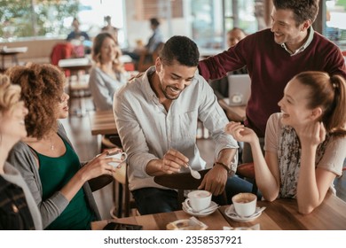 Young and diverse group of people talking while having coffee together in a cafe - Powered by Shutterstock