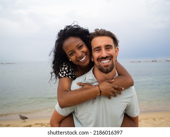 Young Diverse Heterosexual Couple Lovingly Embracing On The Beach During A Sunset. Lovers, Honeymoon. High Quality Photo