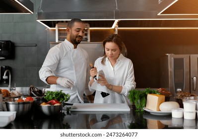 Young diverse male and female chefs in uniform with red wine bottle. Confident professional cooks using wine ingredient at counter in commercial kitchen. Man and woman cooking in professional kitchen. - Powered by Shutterstock