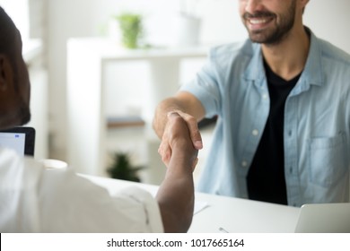 Young diverse multiracial businessmen shaking hands, african american and caucasian entrepreneurs binding contract deal with handshake establishing multi-ethnic partnership concept, close up view