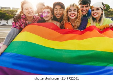 Young diverse people having fun holding LGBT rainbow flag outdoor - Focus on center blond girl - Shutterstock ID 2149922061