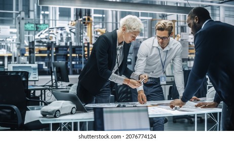Young Diverse Team of Automotive Engineers Working in Office at Car Factory. Industrial Designer Talks About Electric Engine Parts with Colleagues, Discussing Different Technological Applications. - Shutterstock ID 2076774124