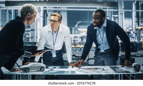 Young Diverse Team of Automotive Engineers Working in Office at Car Factory. Industrial Designer Talks About Electric Engine Parts with Colleagues, Discussing Different Technological Applications. - Shutterstock ID 2076774178