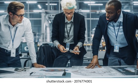 Young Diverse Team Of Automotive Engineers Working In Office At Car Factory. Industrial Designer Talks About Electric Engine Parts With Colleagues, Discussing Technical Blueprint For Mobility Project.