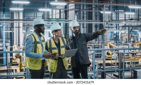 Young Diverse Team Of Car Factory Specialists Working On Laptop And Tablet Computers. Engineers Discussing Automotive Industrial Manufacturing Technology On Modern Vehicle Assembly Plant.