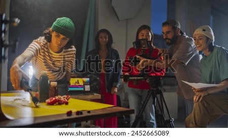 Young Diverse Team Of Cinematographers Engaged In A Lively Video Production Session On A Film Set, Focusing On A Creative Advertising Shoot With Vibrant Lighting And Dynamic Camera Work.