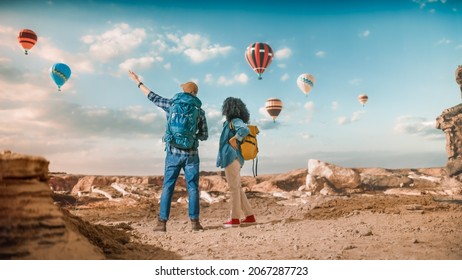 Young Diverse Tourist Couple Hiking with Backpacks in Great Wilderness in Rocky Canyon Valley. Male and Female Backpacker Friends on Adventure Trip. Hot Air Balloon Festival in Mountain National Park. - Powered by Shutterstock