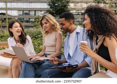 Young Diverse University Students Working Away From Home On Laptop And Tablet Together. Guy With His Girlfriends Is Discussing New Topic Sitting On Street. Technology Concept