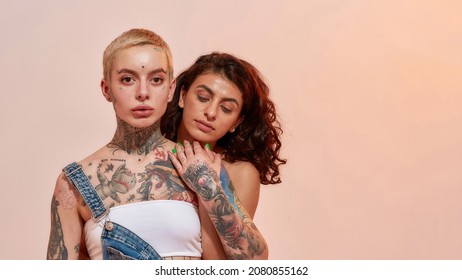 Young diverse women, generation Z lesbian couple embracing while posing together isolated over light pink background. Lgbtq, youth concept. Web Banner - Powered by Shutterstock