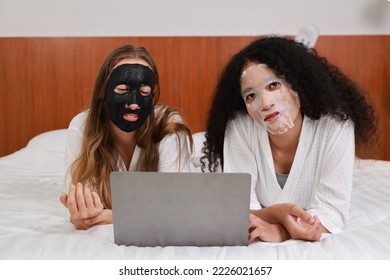 Young diversity ethnic beautiful woman in bathrobe playing social media on computer while doing cosmetic facial mask for skin care and treatment. - Powered by Shutterstock