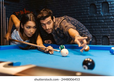 Young diversity group of people playing pool together with smile, enjoyment and fun. Young people spend time in billiards room at the nightclub. Men, women friends playing billiards. Nightlife concept - Powered by Shutterstock