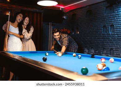 Young diversity group of people playing pool together with smile, enjoyment and fun. Young people spend time in billiards room at the nightclub. Men, women friends playing billiards. Nightlife concept - Powered by Shutterstock