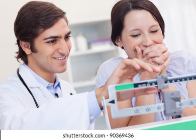 Young doctor adjusting scale for excited patient