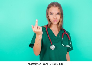 Young Doctor Caucasian Girl Wearing Medical Uniform Over Green Background Shows Middle Finger Bad Sign Asks Not To Bother. Provocation And Rude Attitude.