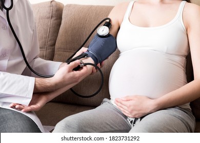 Young Doctor Is Checking Blood Pressure Of Pregnant Woman At Home. High Pressure Problem During Pregnancy Concept.