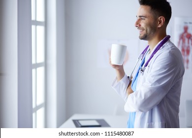 Young Doctor With Coffee Cup In Medical Office